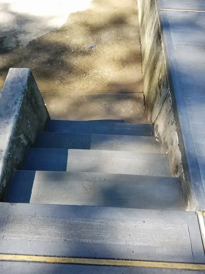 Clean concrete steps descend between sturdy walls toward a lower landing.