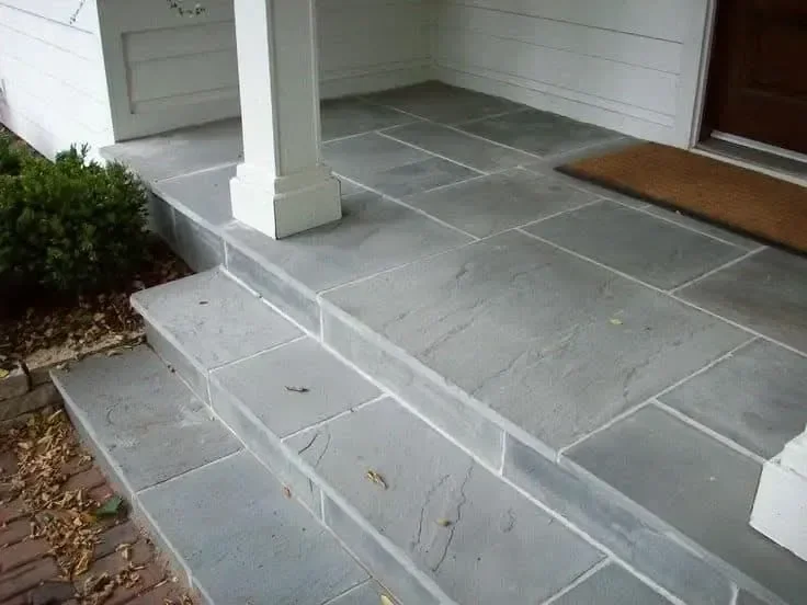Gray stone steps lead to a bright residential porch and entry door.