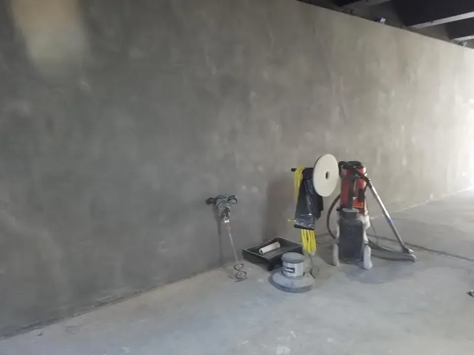 Floor polishing equipment rests against a textured masonry wall during cleaning.