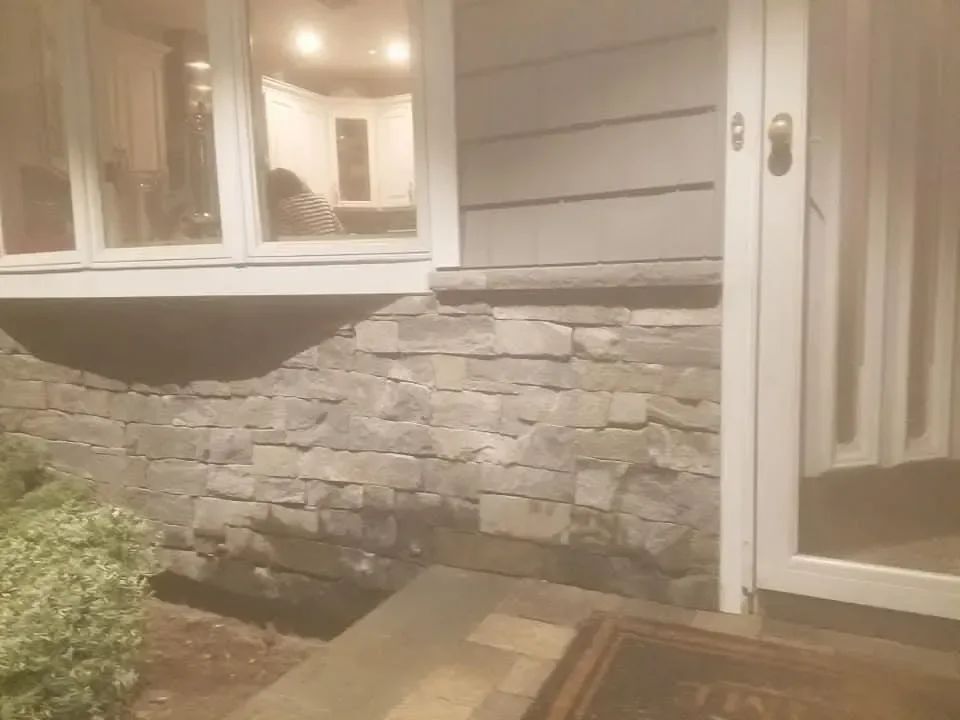 Evening lighting highlights spotless stacked stone beneath modern siding.