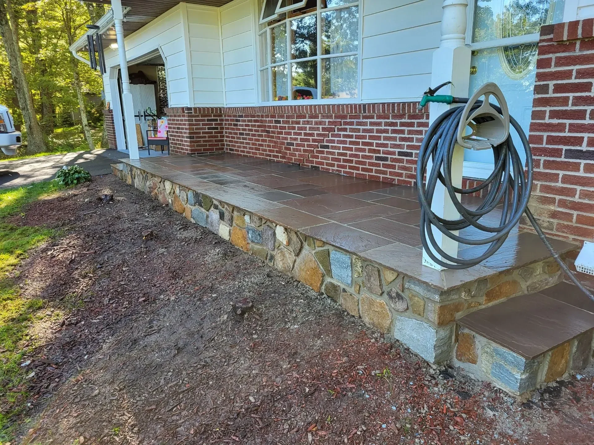 A finished porch showcases multicolored stone veneer and dark slate tile flooring.