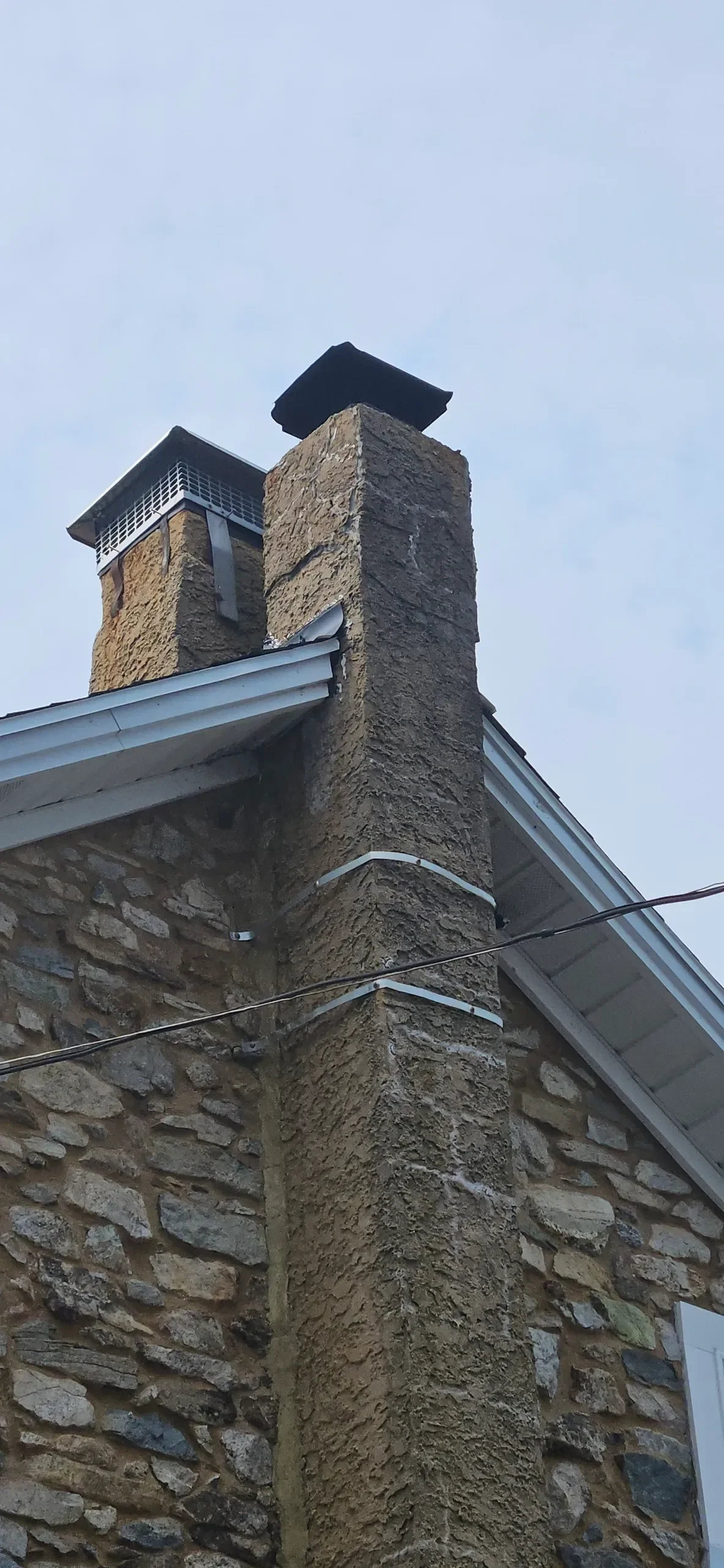 Textured stucco chimneys rise above a neatly cleaned stone wall.